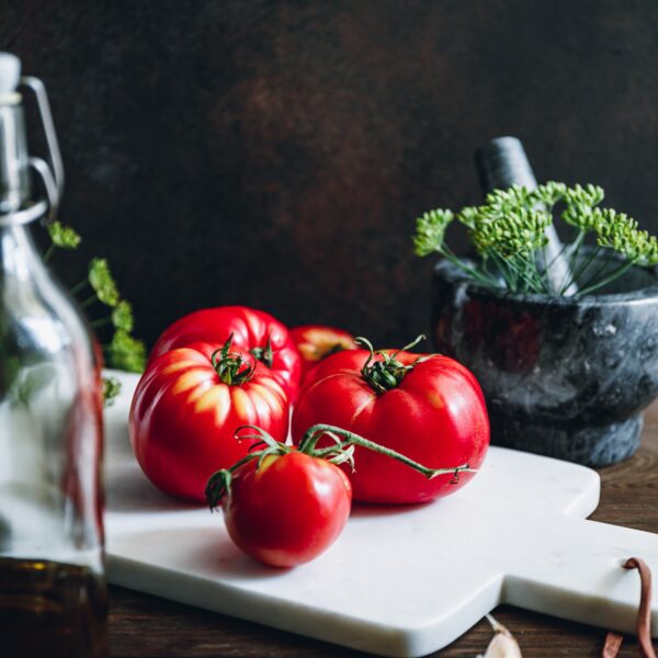 Ripe tomatoes on a white marble kitchen board. Cooking concept.